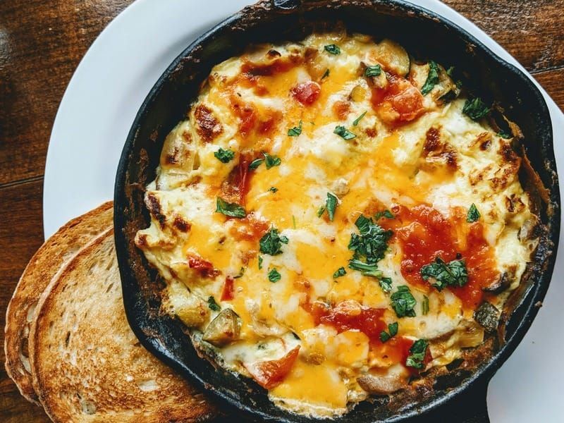 A frittata with vegetables and herbs in a cast-iron skillet